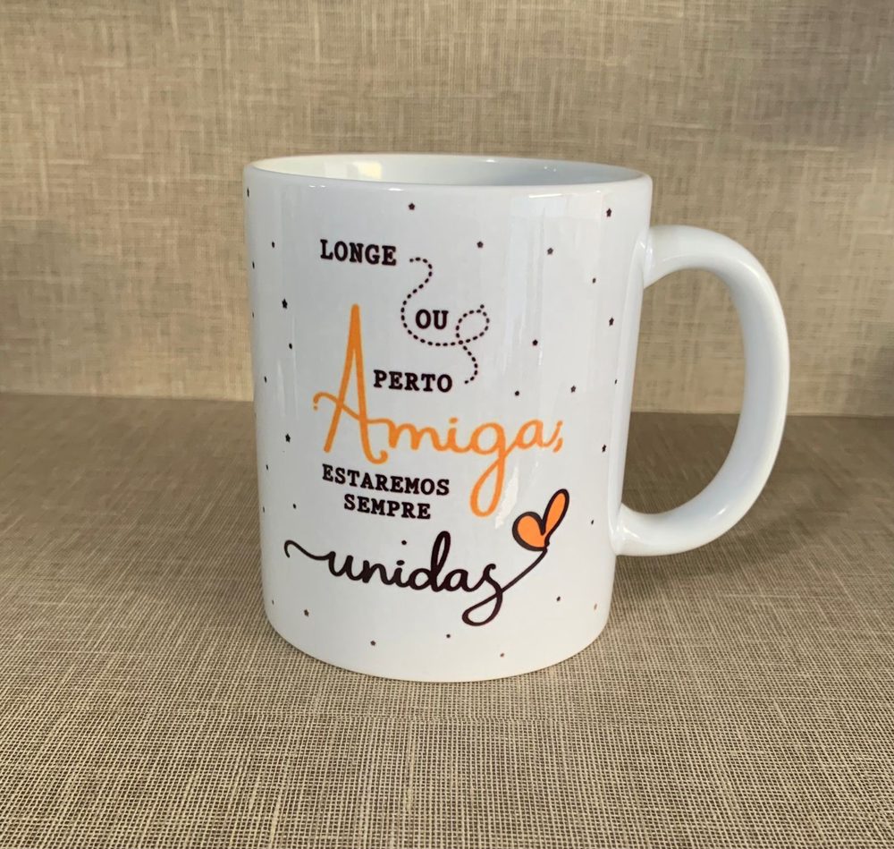 Caneca branca com letras laranja e a frase Longe ou perto amiga estaremos sempre unidas